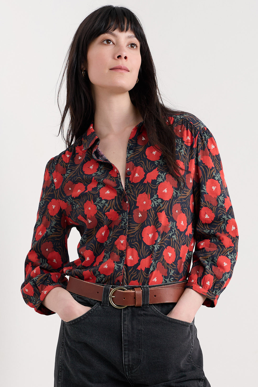 Woman wearing a black floral blouse with red flowers on a white background