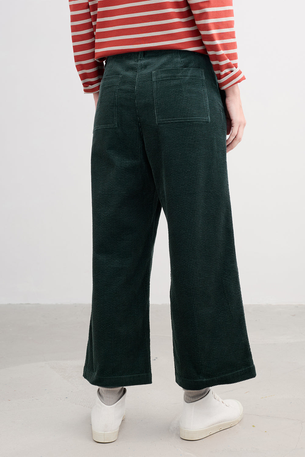 Person wearing green wide-leg pants and a red and white striped shirt on a plain background