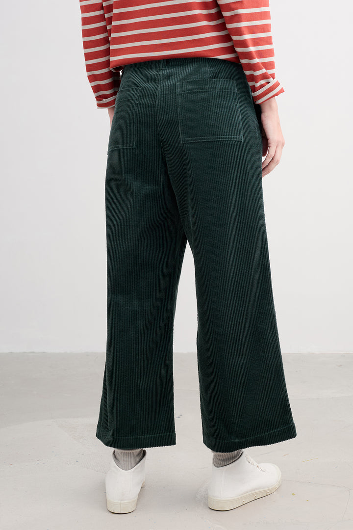 Person wearing green wide-leg pants and a red and white striped shirt on a plain background