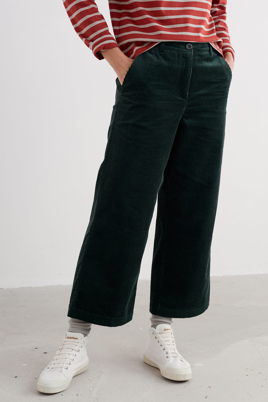 Person wearing a red and white striped sweater with dark green wide-leg pants on a plain background