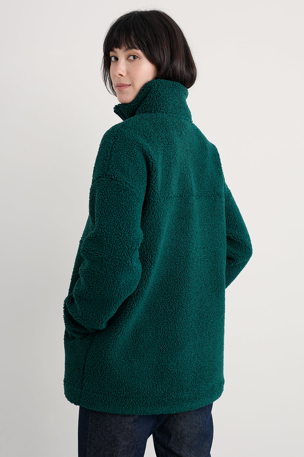 Person wearing a green fleece jacket on a plain background