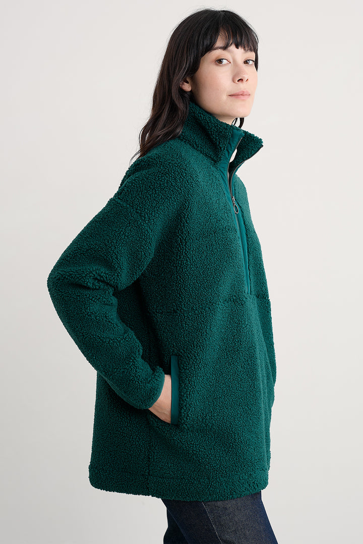 Person wearing a green fleece jacket on a plain background