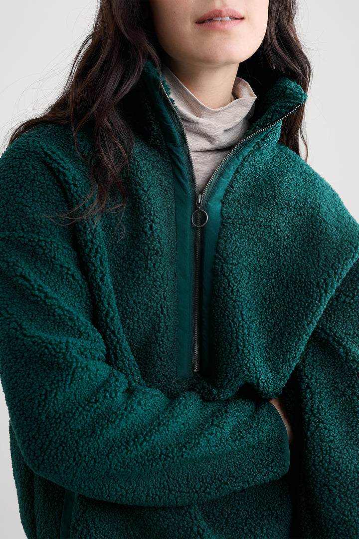 Person wearing a teal fleece jacket with a neutral background
