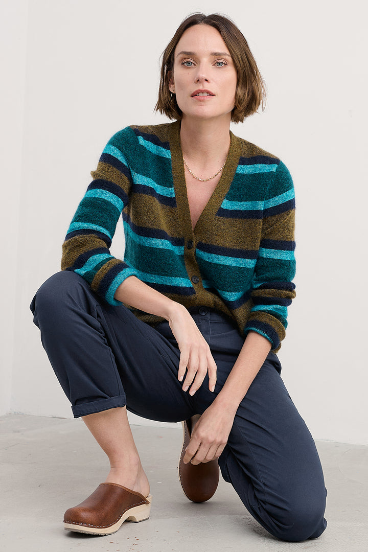Woman wearing a striped sweater and navy pants on a white background
