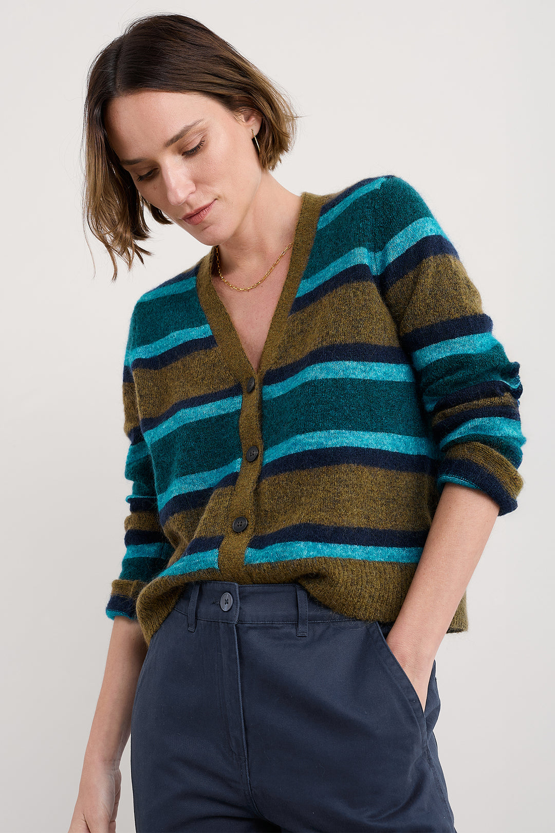 Woman wearing a striped sweater with green, blue, and brown colors on a white background