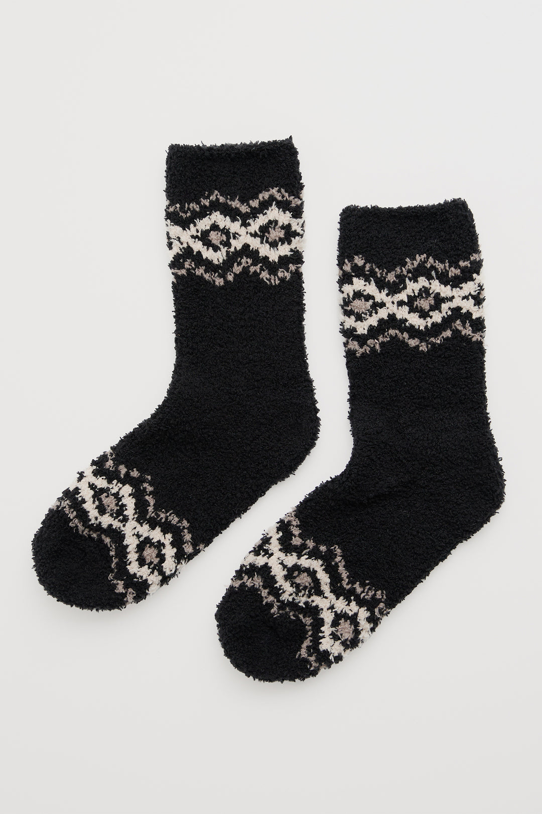 Pair of black socks with patterned toes and cuffs on a light gray background