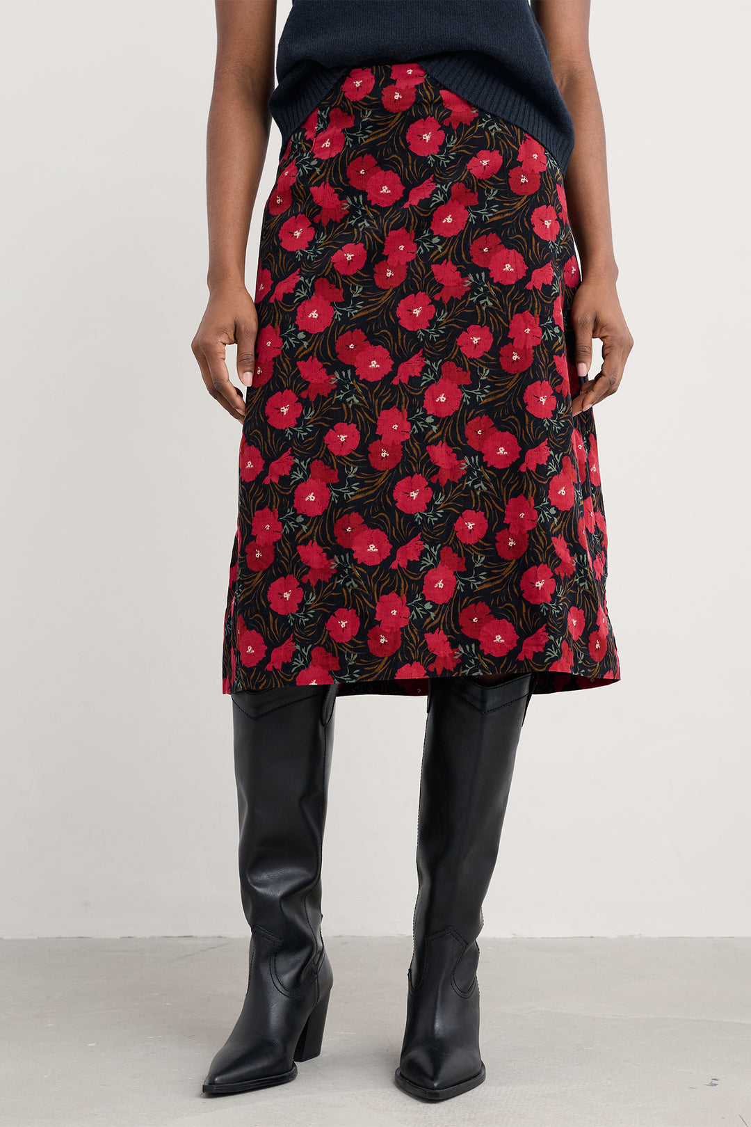 Person wearing a red floral skirt with black background