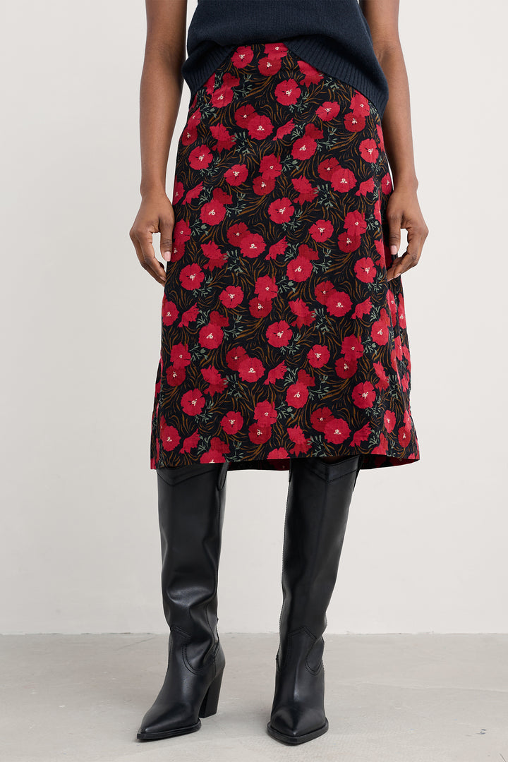 Person wearing a red floral skirt with black background