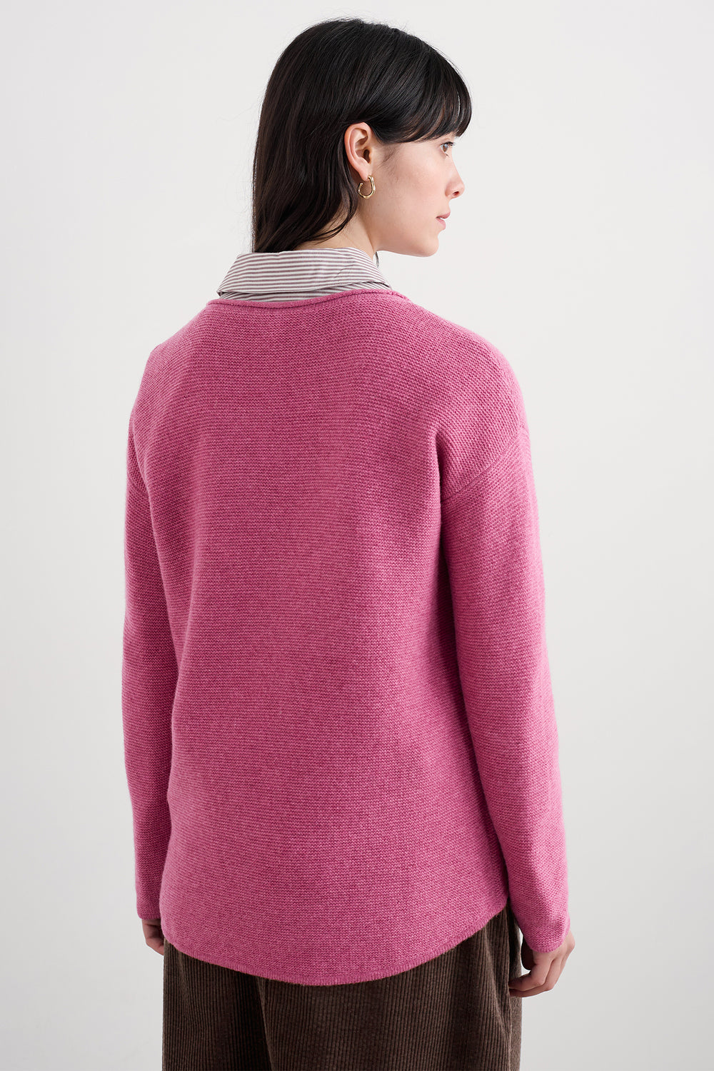 Person wearing a pink sweater with a white background