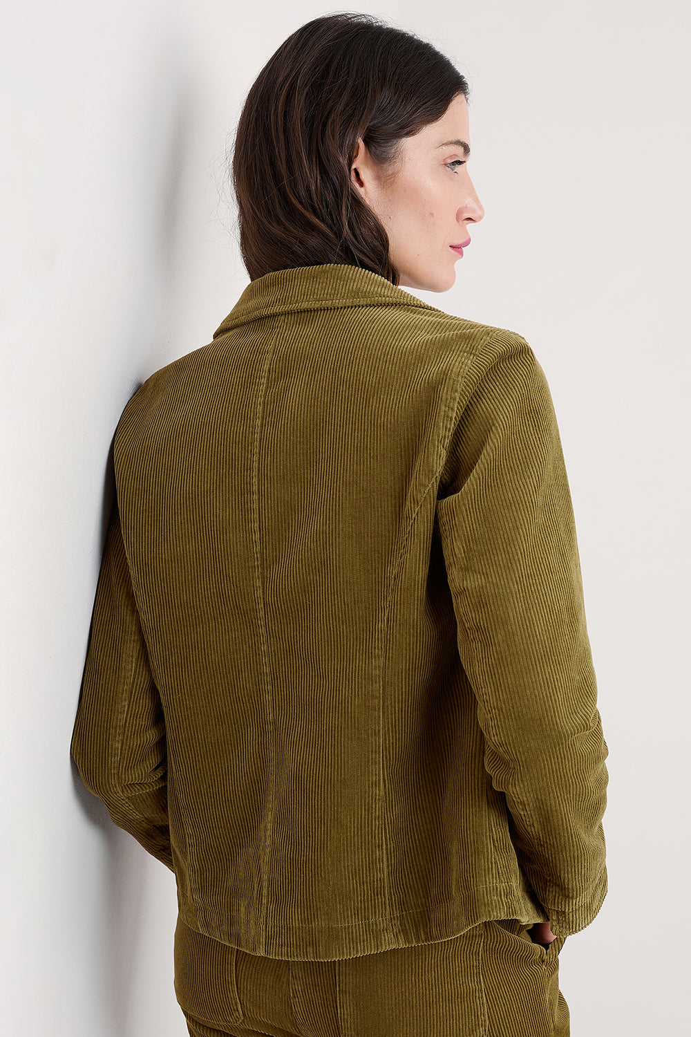 Woman wearing a green corduroy jacket against a white background