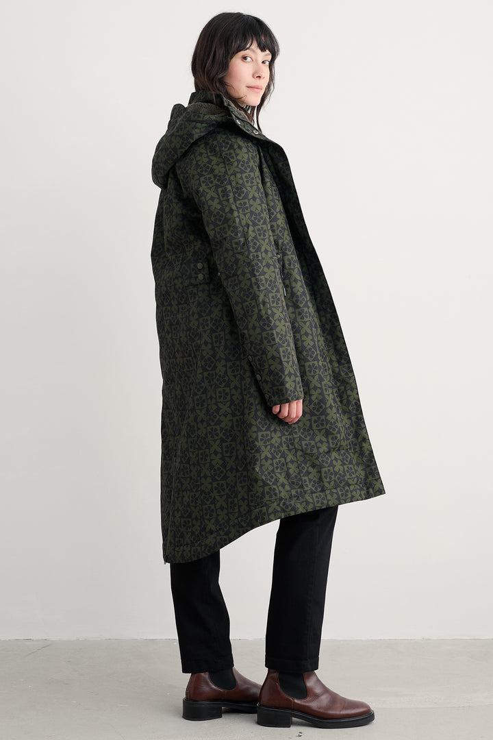 Person wearing a long green coat with a hood on a plain background