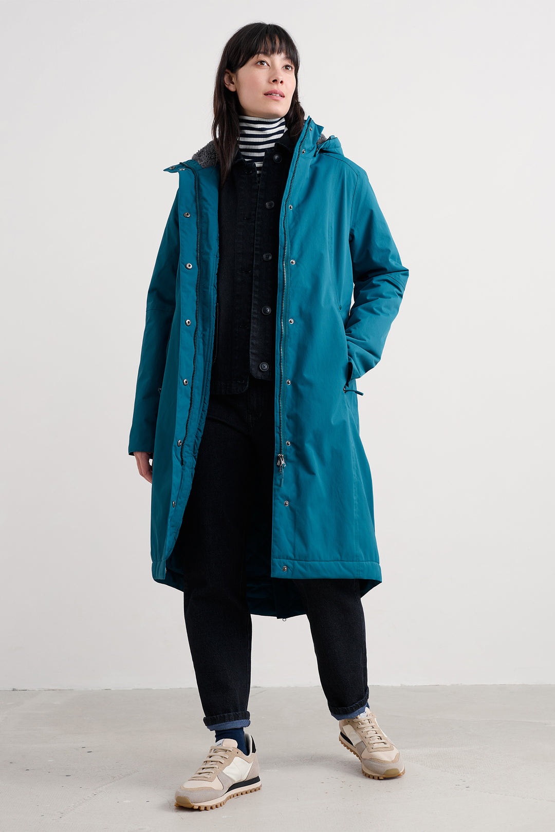 Person wearing a teal coat on a white background