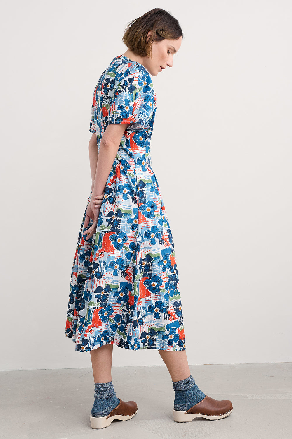 Woman wearing a colorful floral dress on a plain background