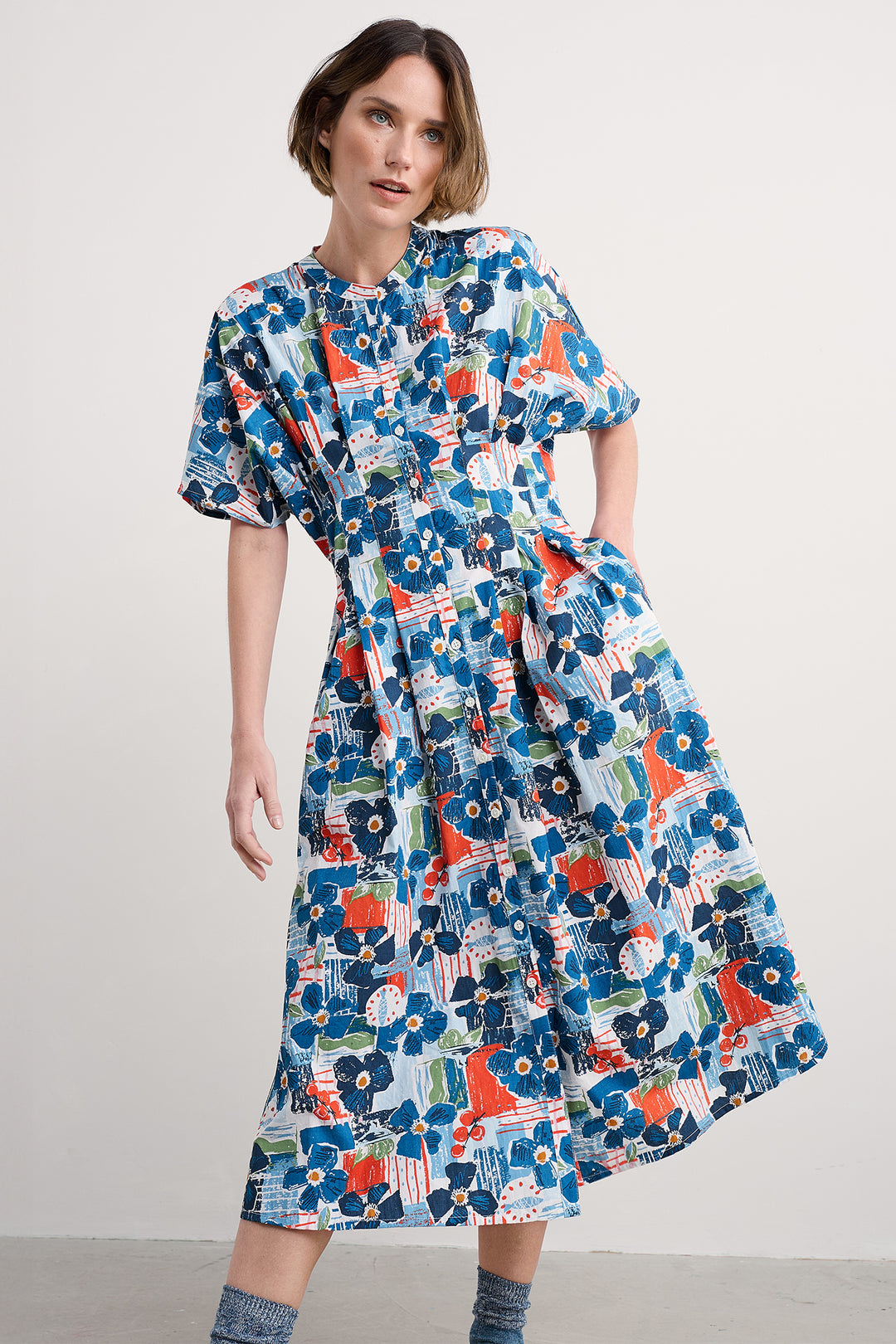 Woman wearing a colorful floral dress against a plain background