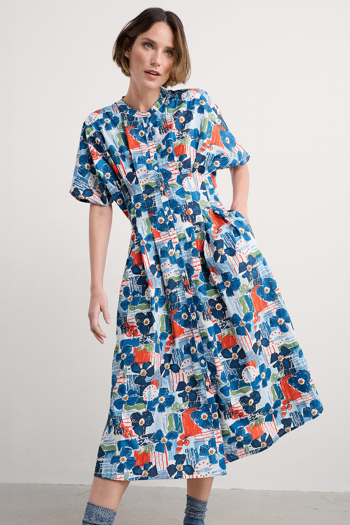 Woman wearing a colorful floral dress against a plain background