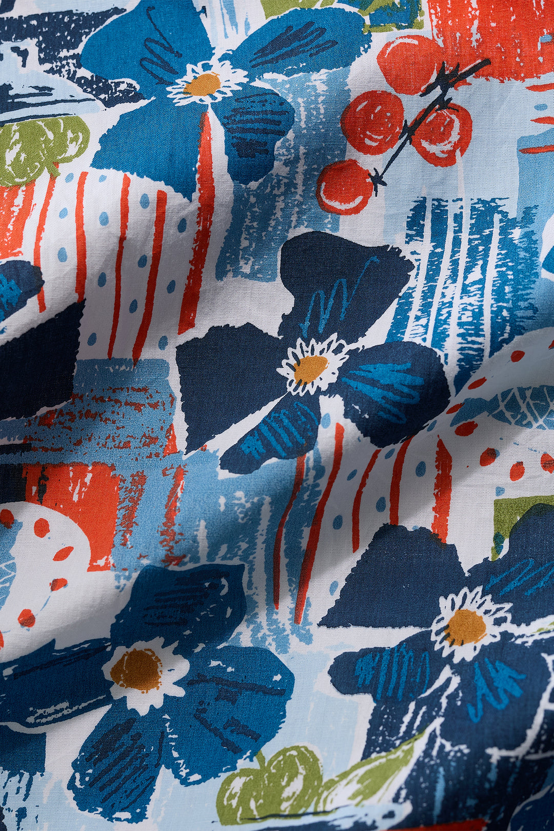 Close-up of a fabric with blue floral and abstract patterns in red, white, and green.