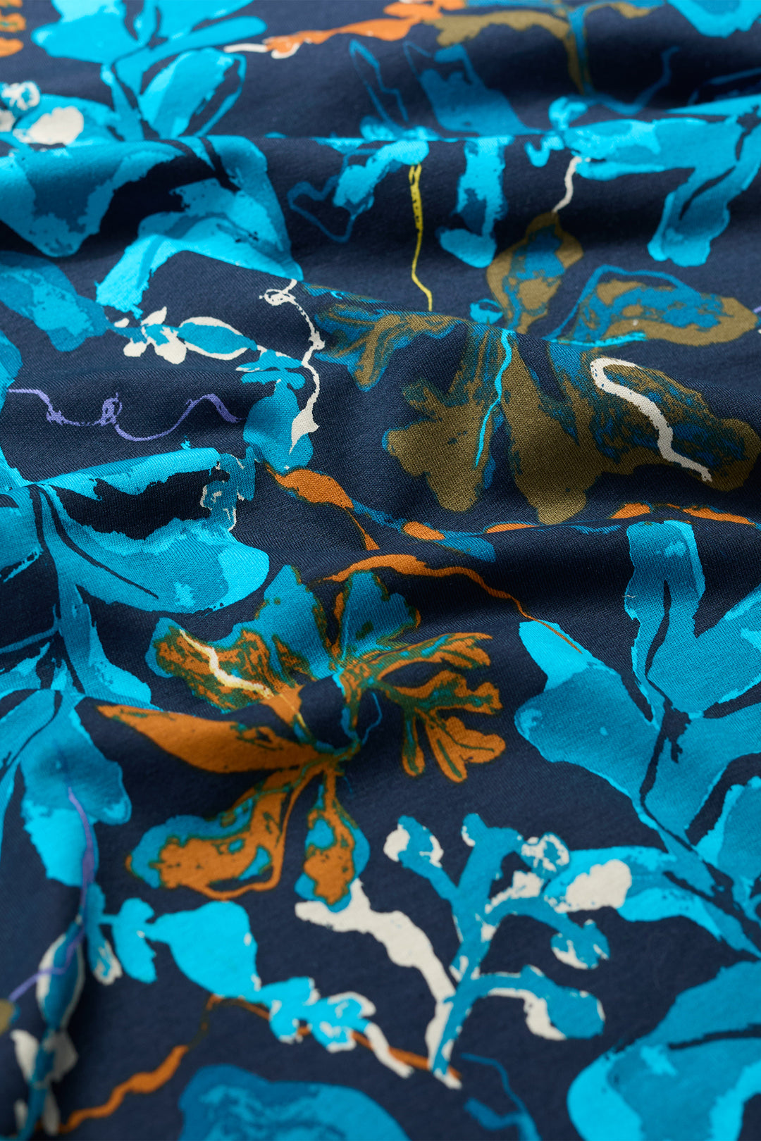 Close-up of floral fabric with blue, orange, and white flowers on a navy background