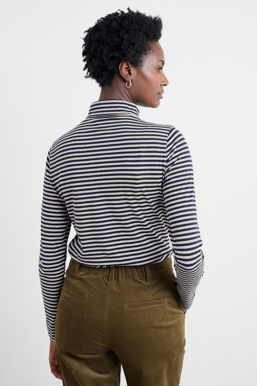 Person wearing a navy and white striped shirt with brown pants on a plain background