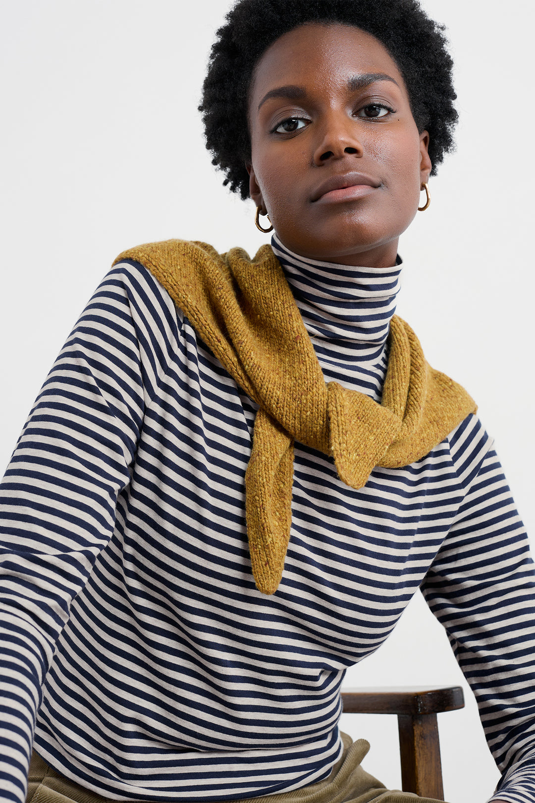 Person wearing a yellow scarf and striped shirt against a white background