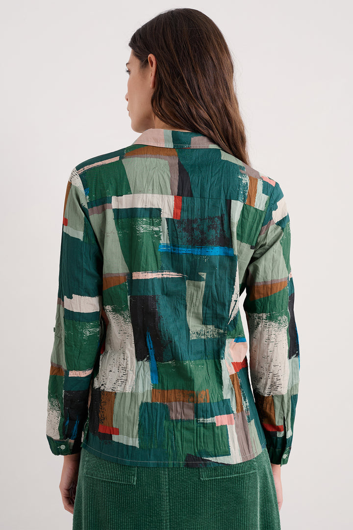 Person wearing a colorful geometric-patterned shirt on a white background