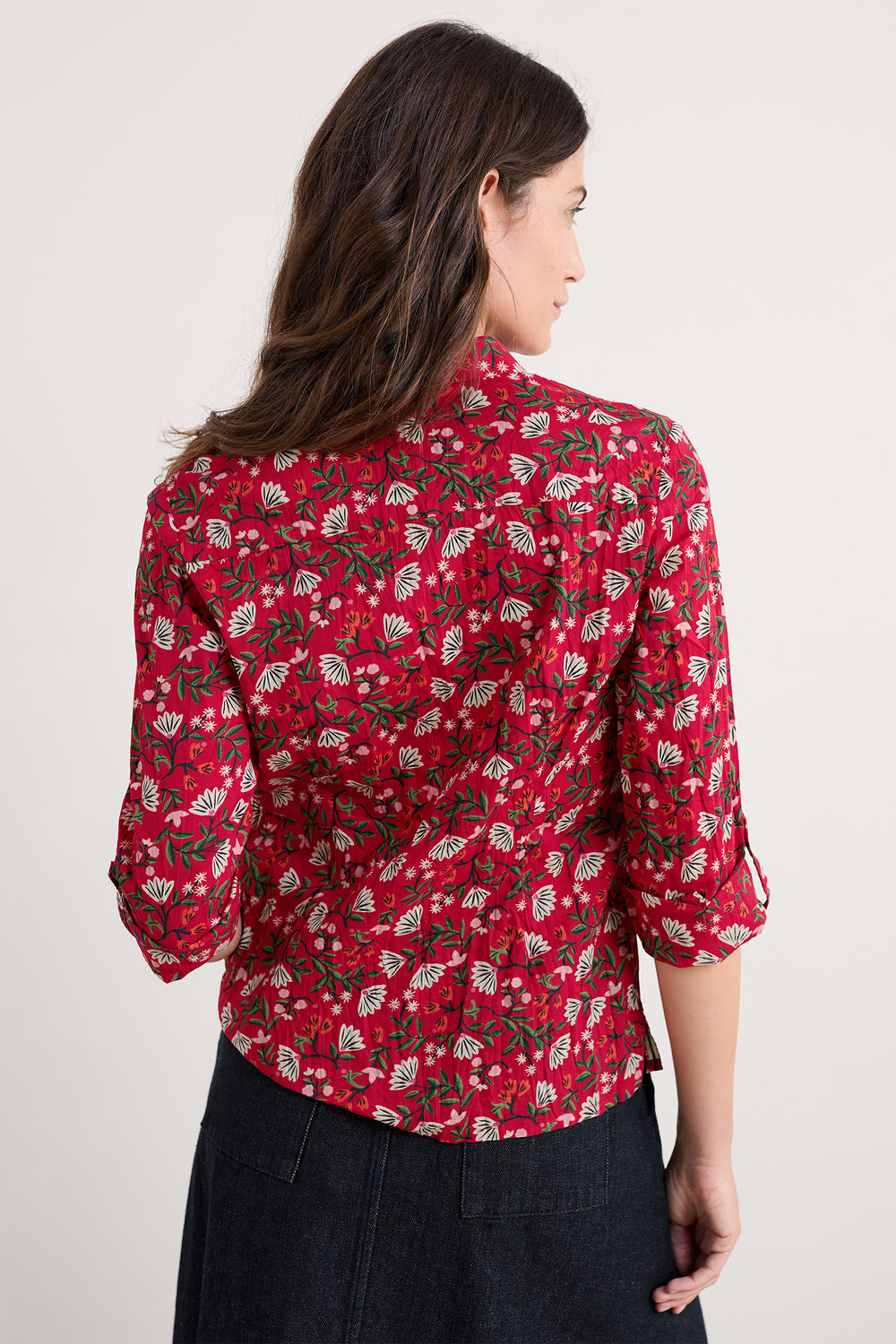 Woman wearing a red floral patterned shirt against a plain background