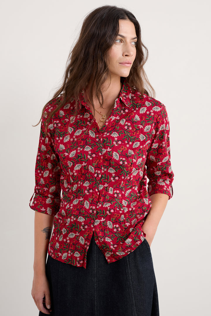 Woman wearing a red floral patterned shirt against a plain background