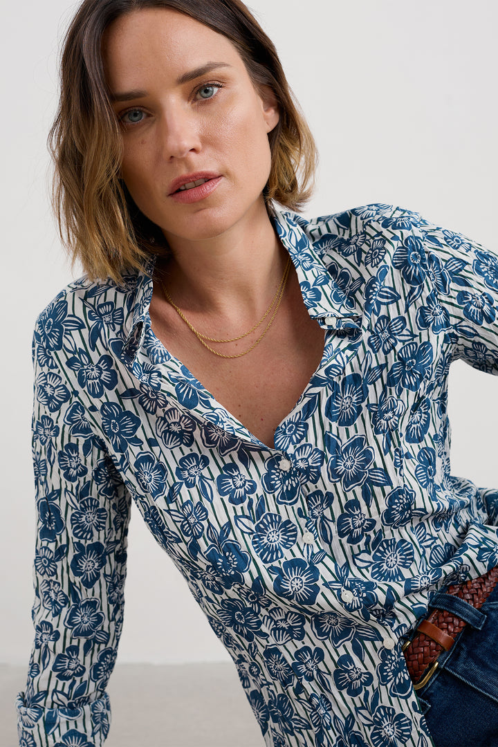 Woman wearing a blue floral patterned shirt against a white background