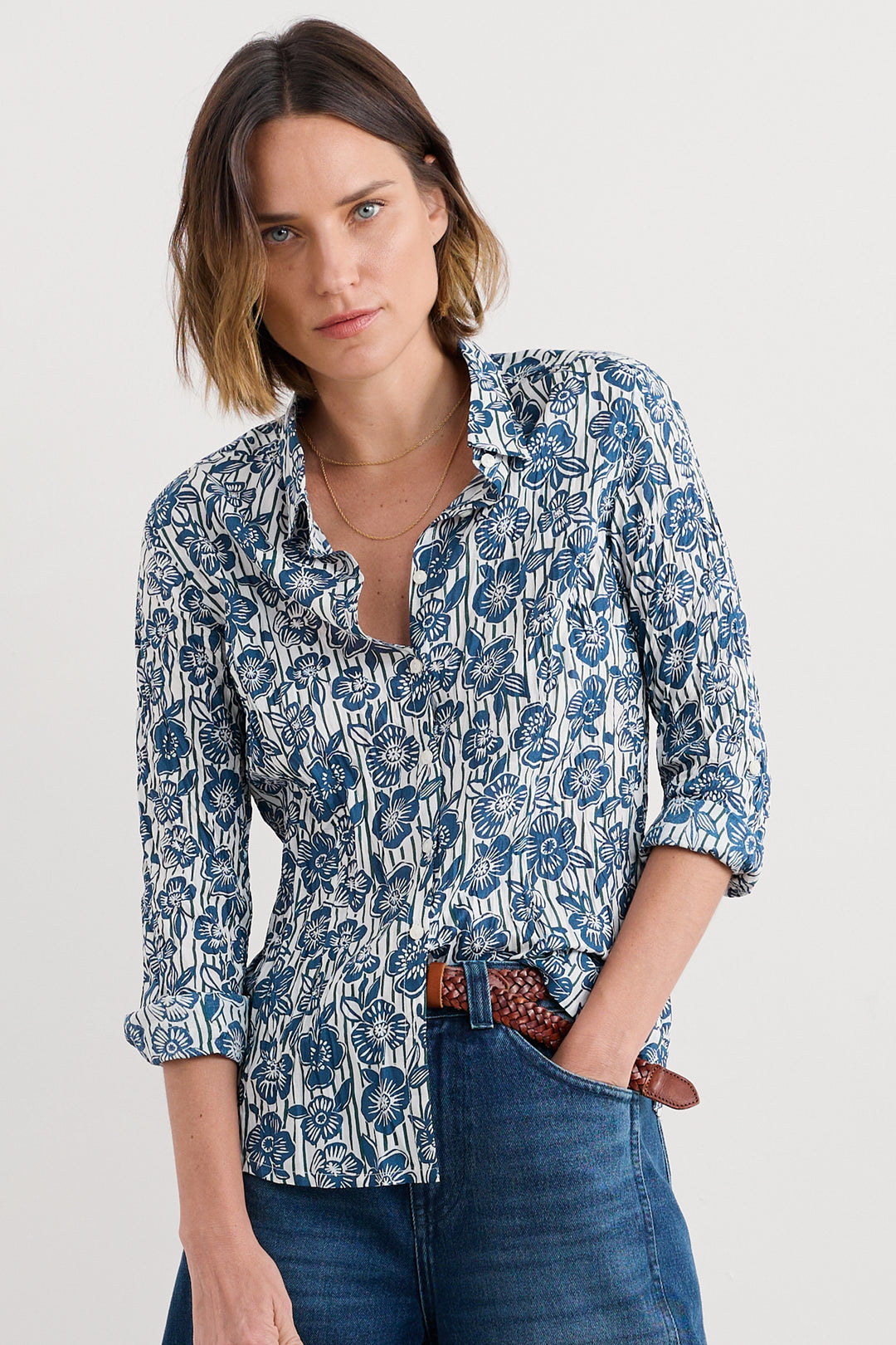 Woman wearing a blue floral blouse and jeans on a white background