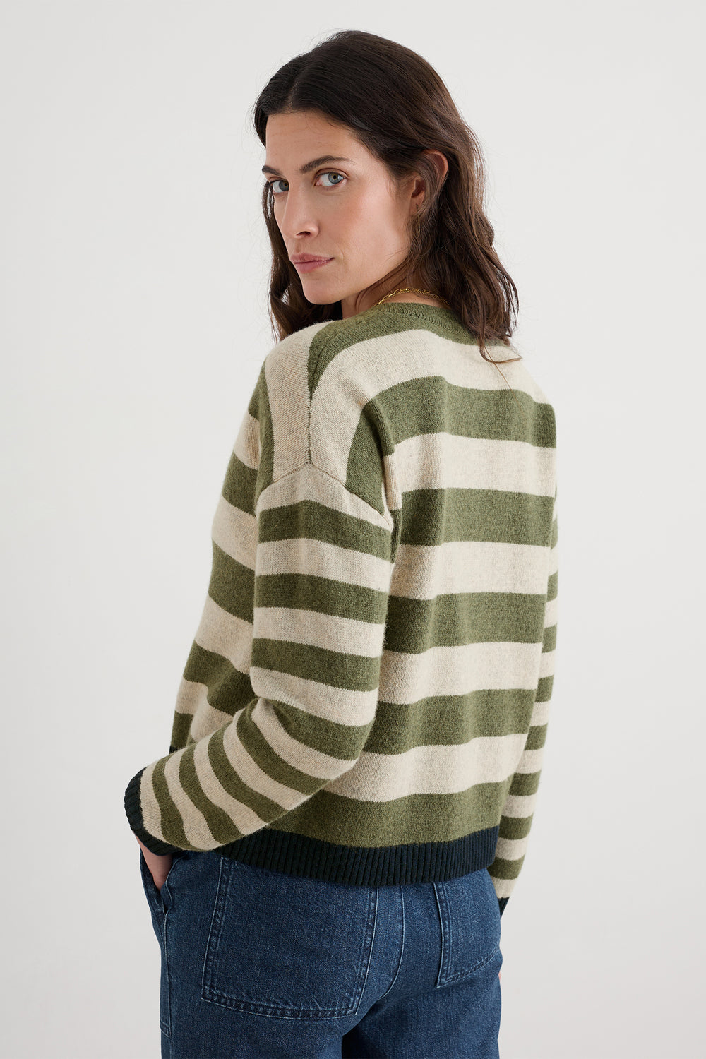 Woman wearing a green and beige striped sweater on a white background