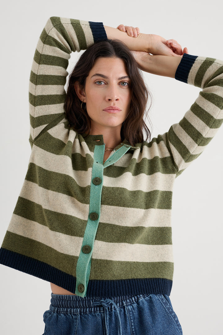 Woman wearing a green and beige striped cardigan with a white background