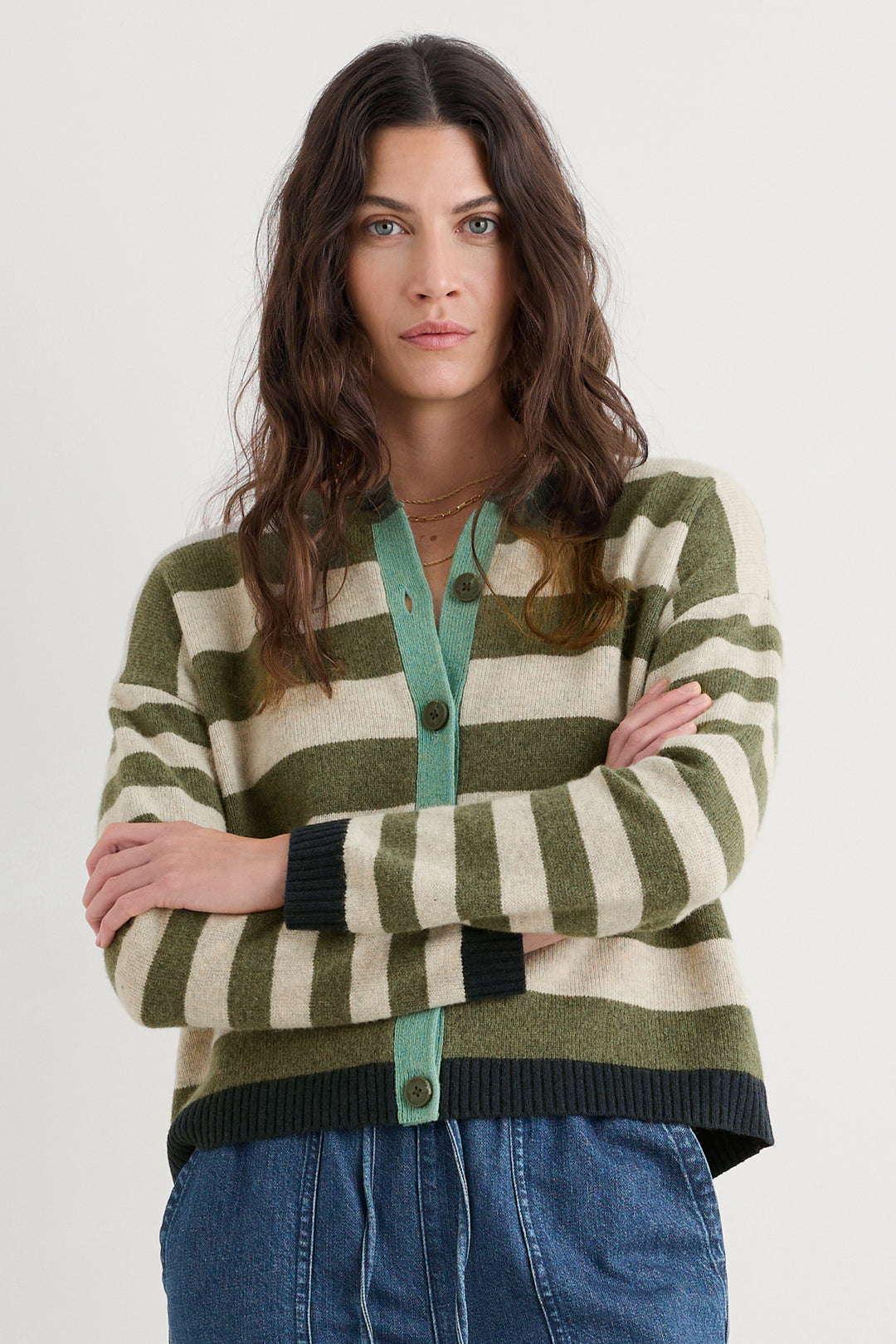 Woman wearing a striped sweater with green, beige, and black colors on a white background