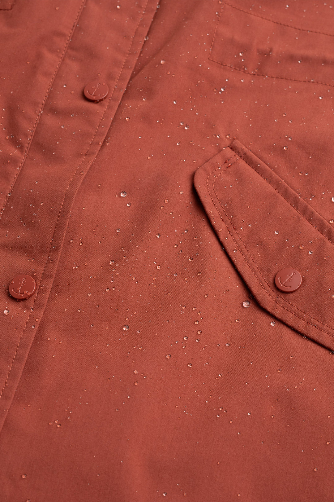 Close-up of a brown fabric texture with buttons and a pocket.