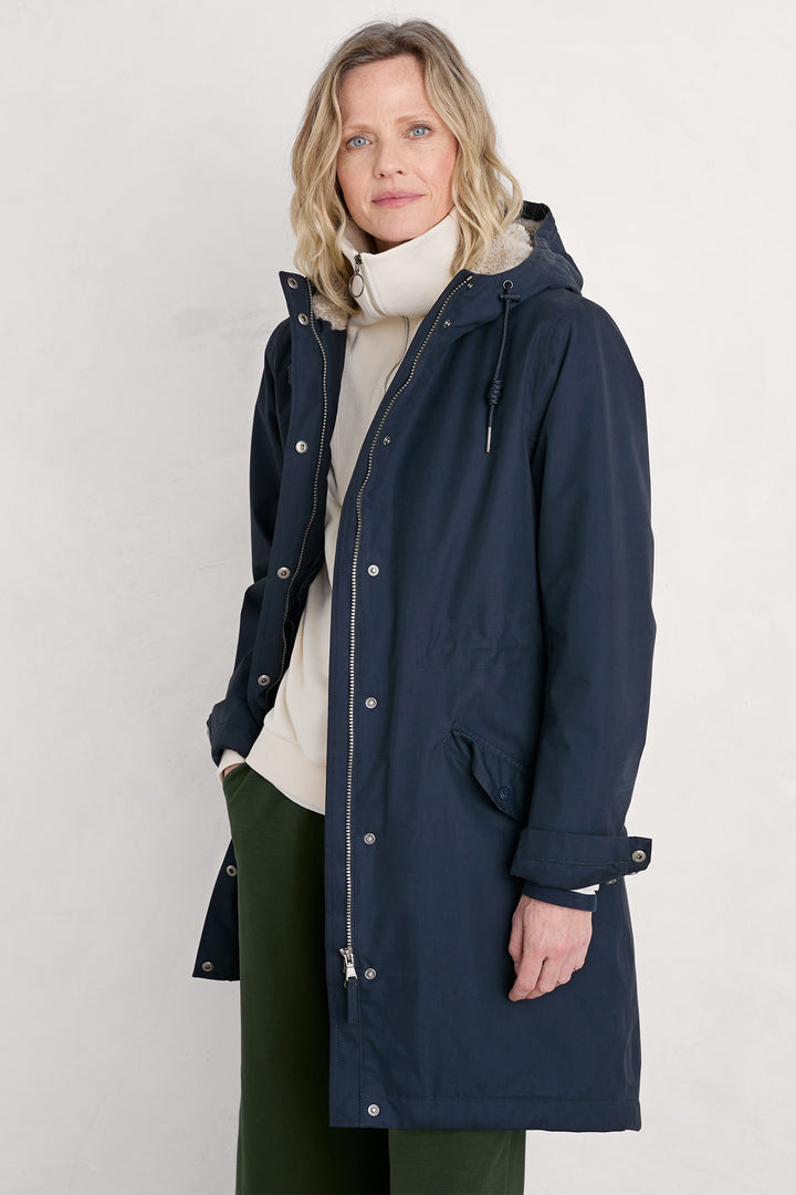 Woman wearing a navy raincoat on a white background
