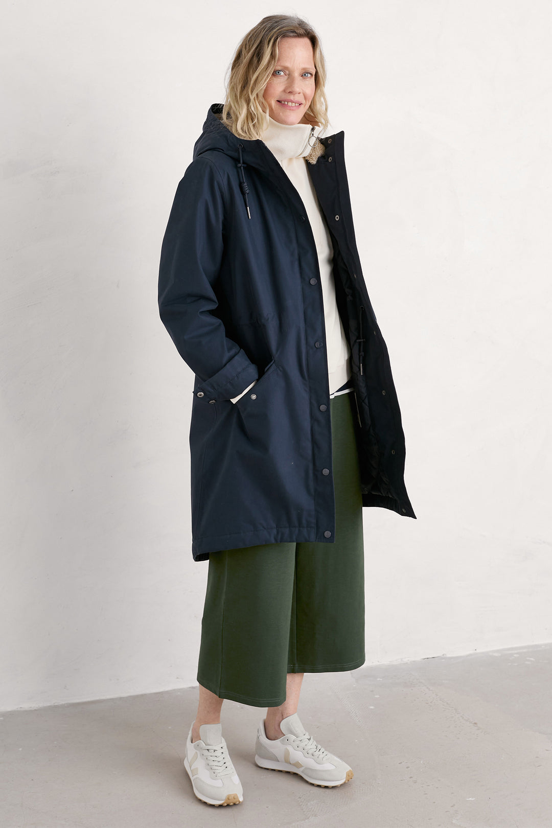 Woman wearing a navy raincoat with a white background