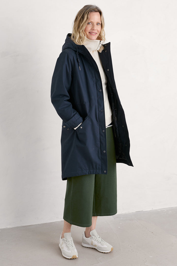 Woman wearing a navy raincoat with a white background