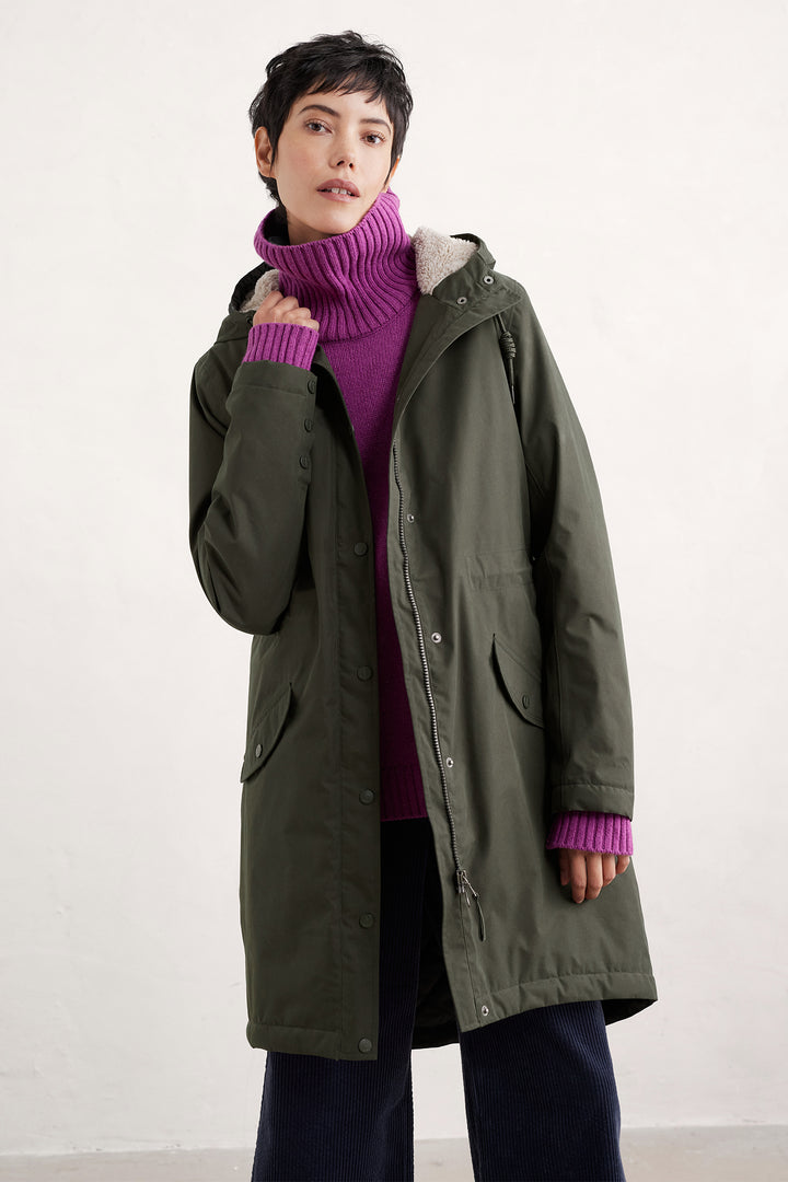 Person wearing a green coat and purple sweater on a white background