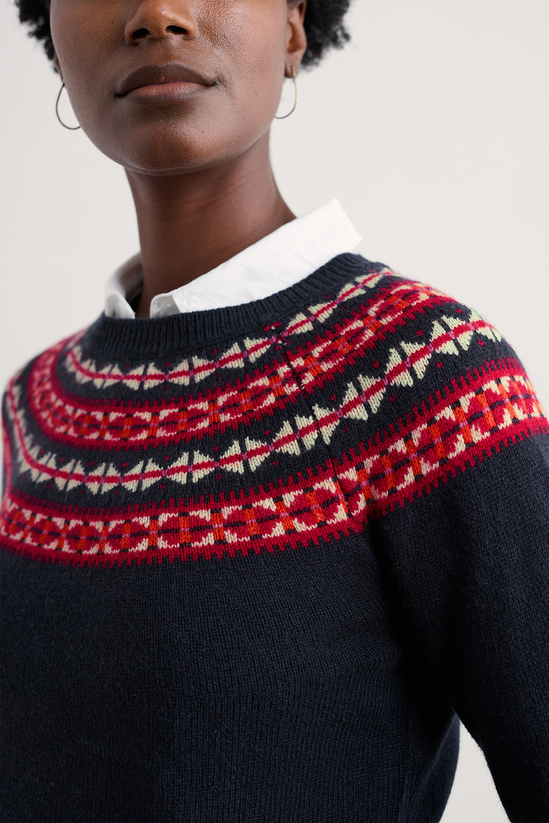 Person wearing a dark blue sweater with a red and white patterned yoke.