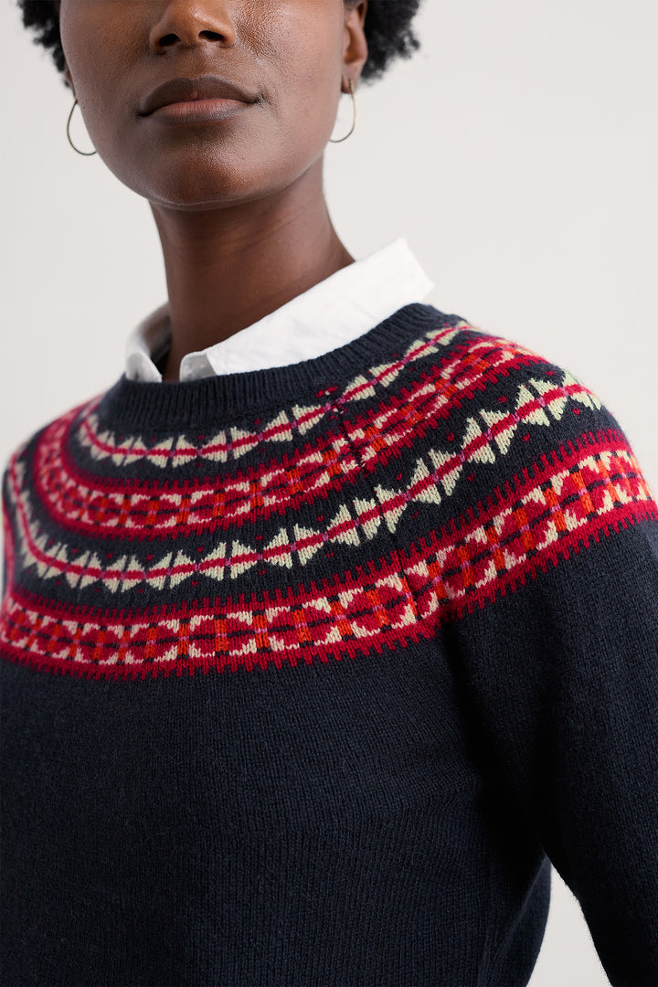 Person wearing a dark blue sweater with a red and white patterned yoke.