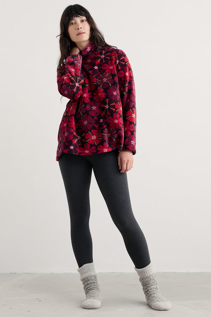 Person wearing a red patterned jacket, black leggings, and gray socks on a white background