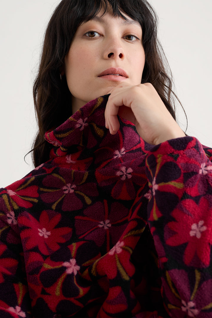 Person wearing a red floral patterned garment against a white background