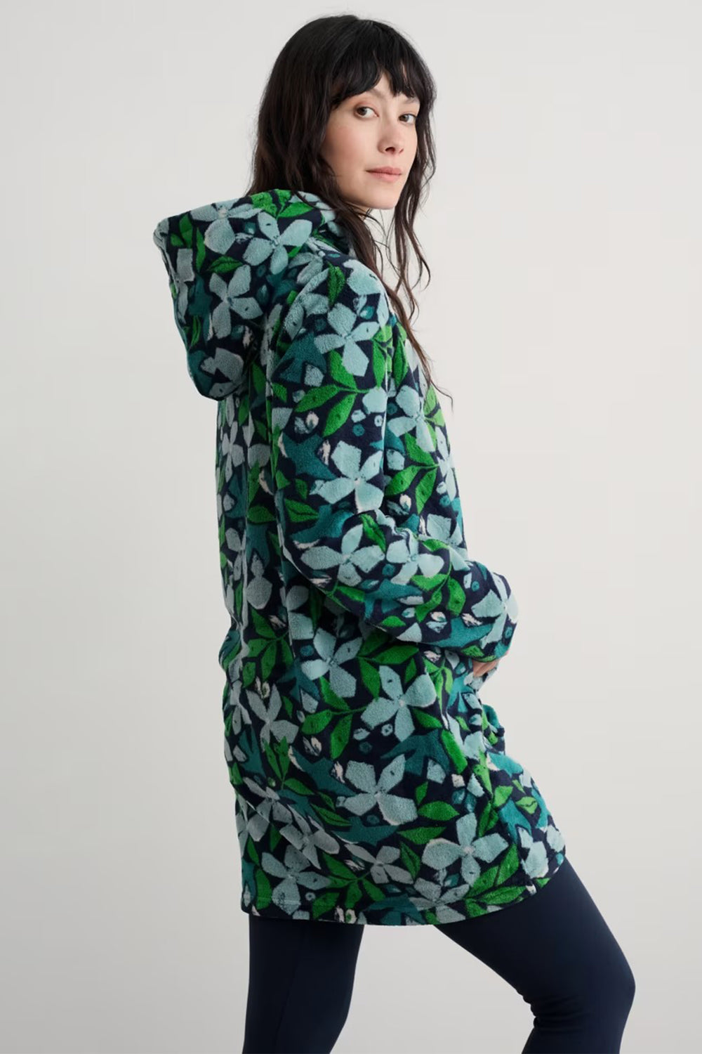 Woman wearing a green floral patterned coat on a white background