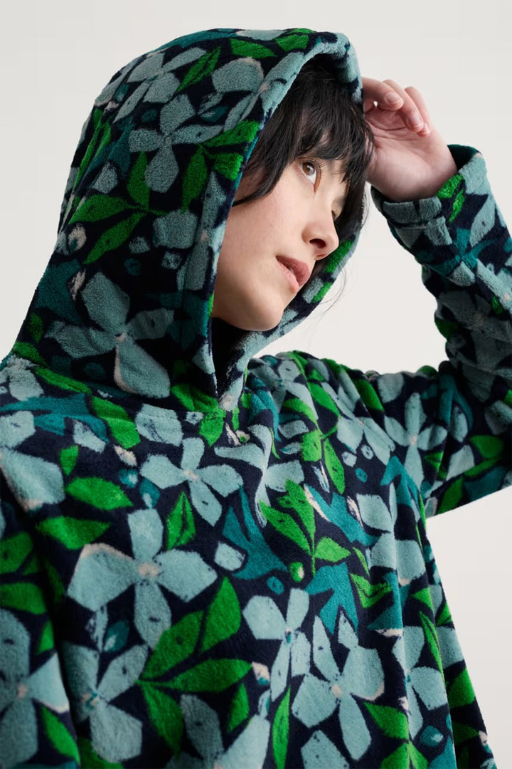 Person wearing a floral patterned hoodie against a plain background