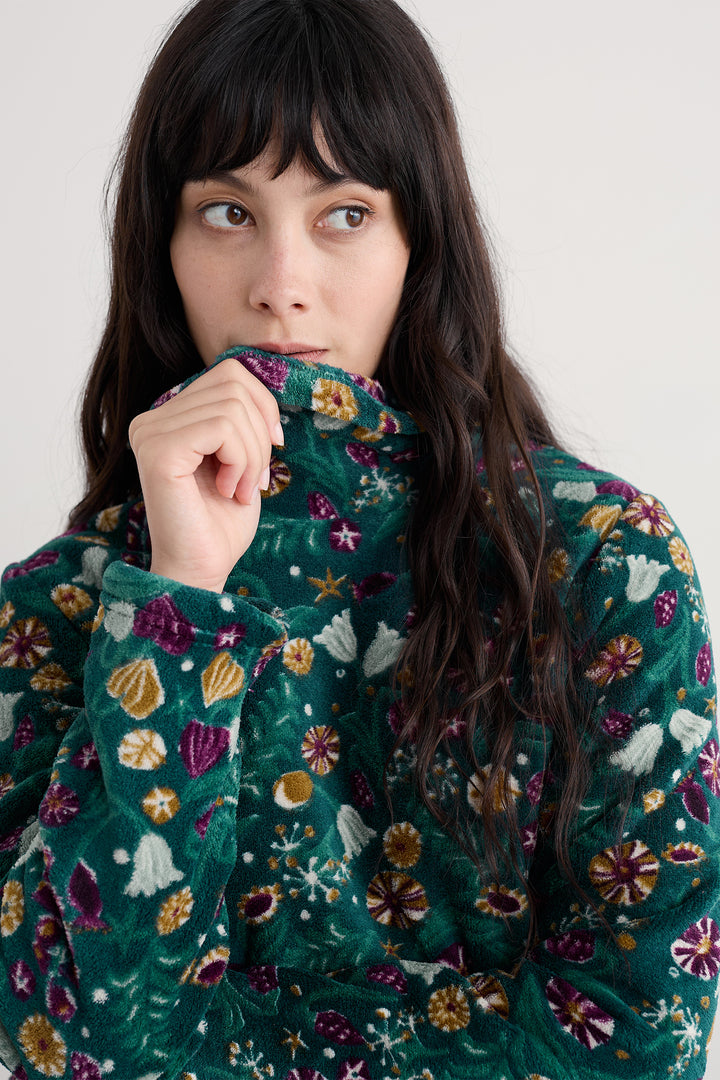 Person wearing a teal floral-patterned sweater against a plain background