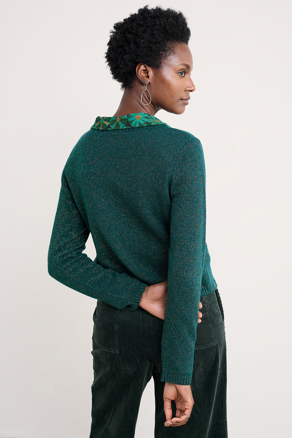 Person wearing a green sweater with a textured collar against a plain background