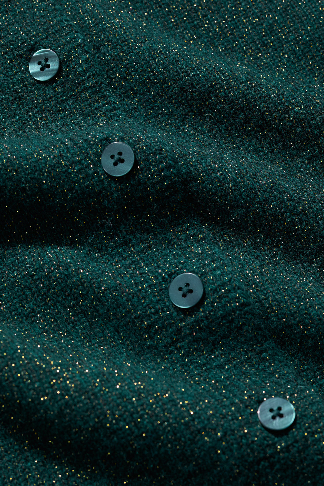 Close-up of dark green fabric with buttons on a textured background