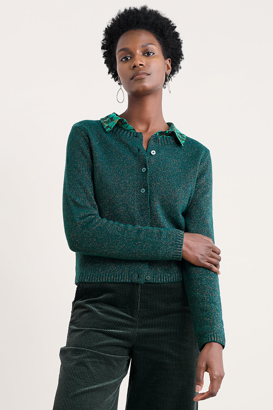 Woman wearing a green knitted cardigan against a plain background