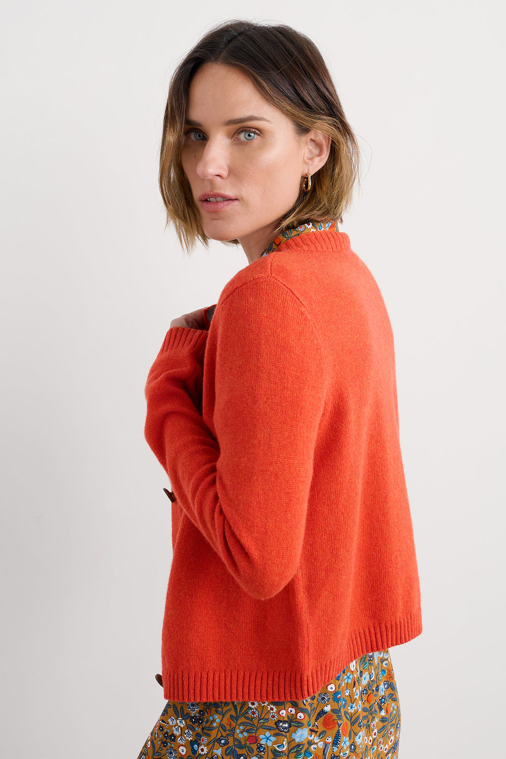 Woman wearing an orange sweater on a white background