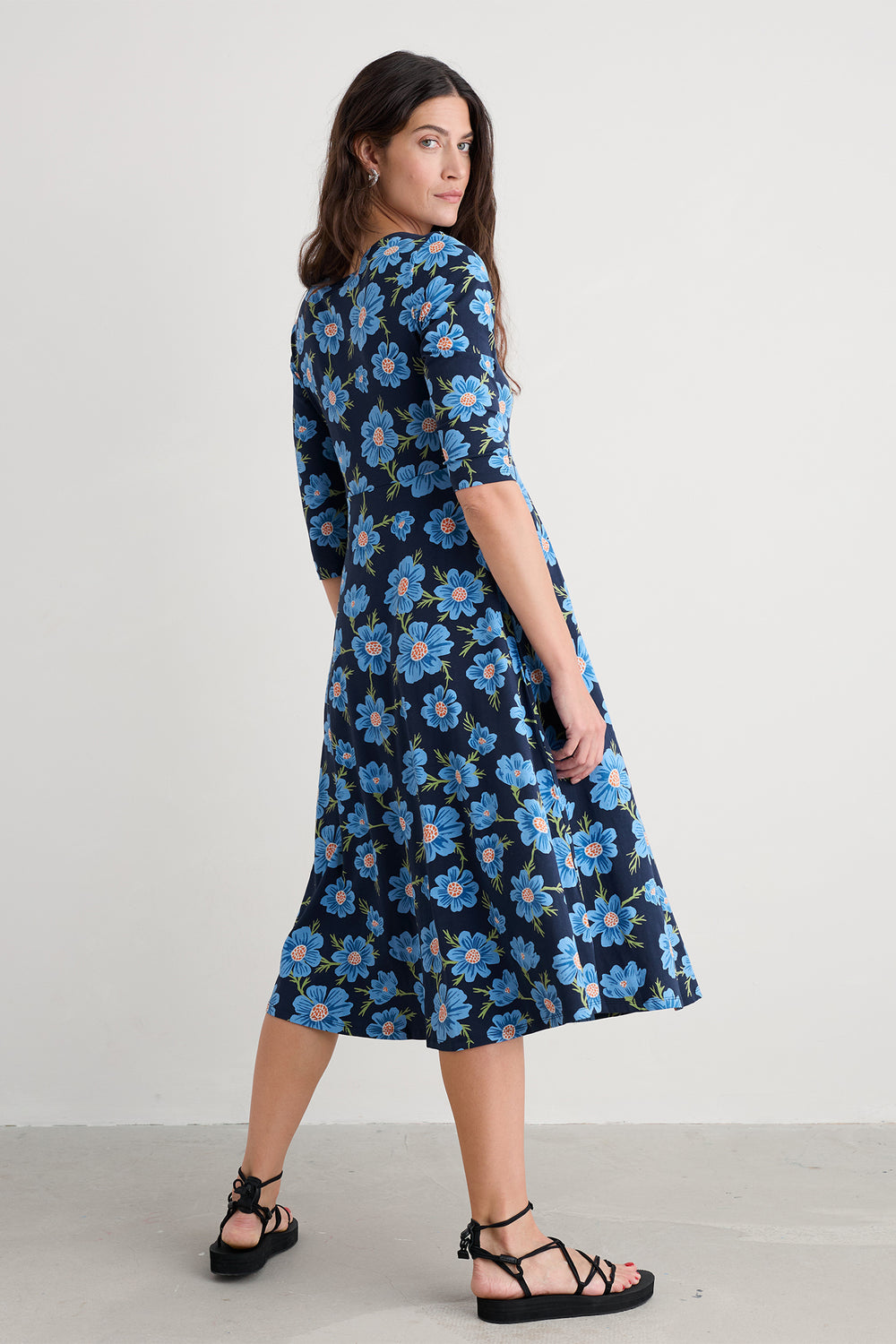 Woman wearing a blue floral dress on a plain background