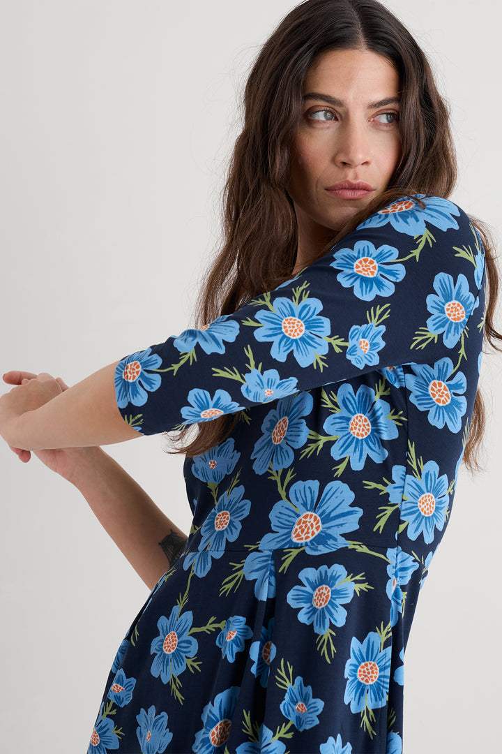 Woman wearing a navy dress with blue floral pattern on a white background