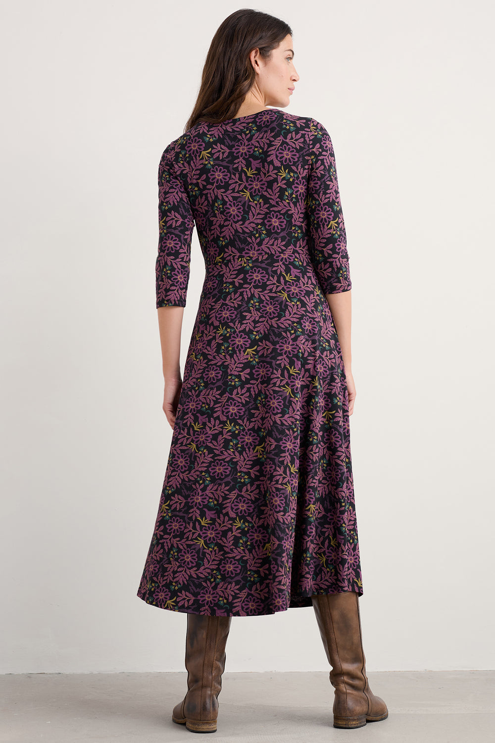 Woman wearing a purple floral dress on a plain background